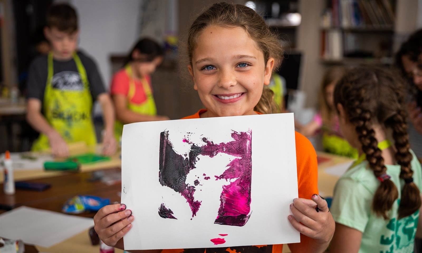 Girl holds up piece of artwork